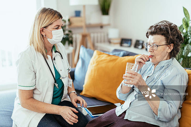 在家吃药，护士在家庭护理期间检查她的健康的年长女人图片素材