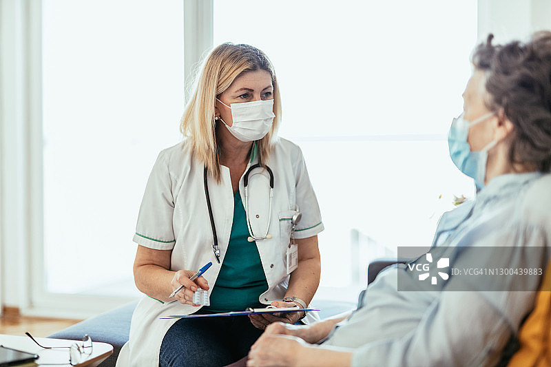 新冠疫情期间，年长的妇女和护士在家中进行快速体检图片素材