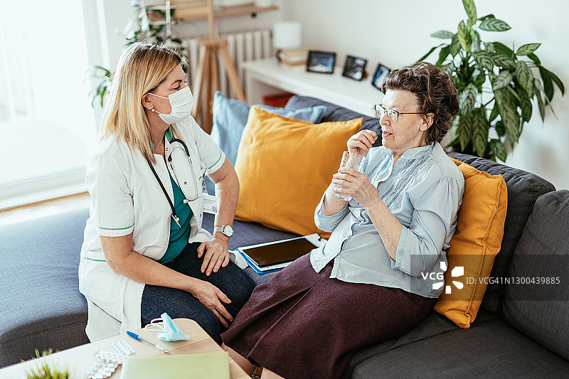 在家吃药，护士在家庭护理期间检查她的健康的年长女人图片素材
