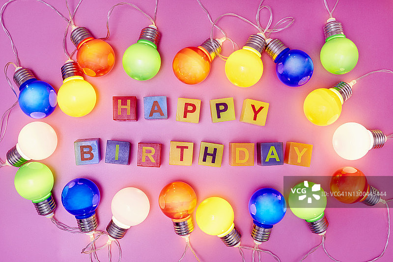 粉色背景上的彩色灯串和生日快乐字母图片素材