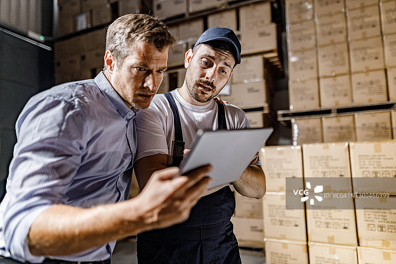 检查员与仓库工人一起在储藏室使用平板电脑图片素材