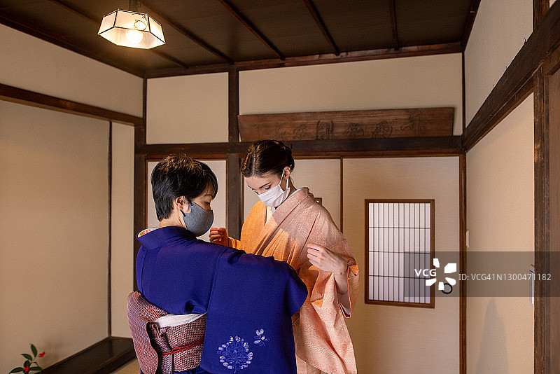 专业和服穿戴师协助年轻女人穿和服图片素材