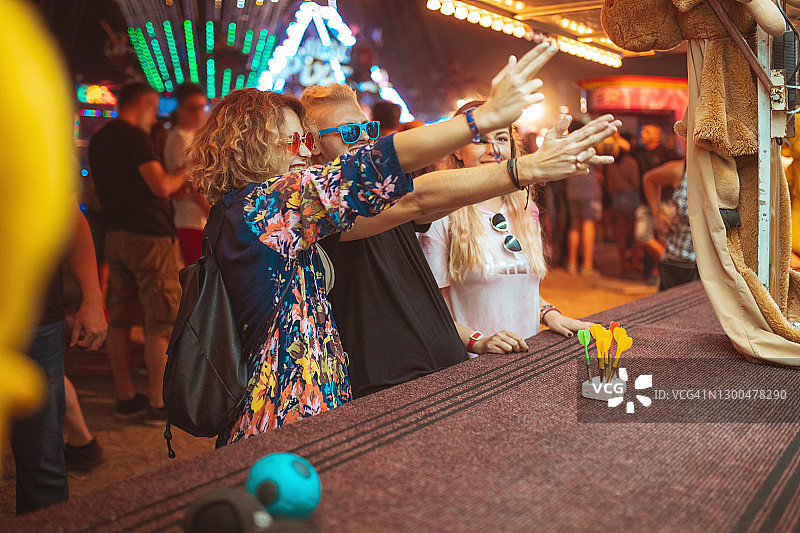 在游乐园里，年轻的朋友们用手假装射击图片素材