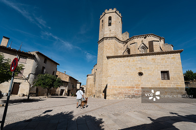 男人和狗在圣玛丽亚拉马约尔教堂主 фасадом 前行走图片素材