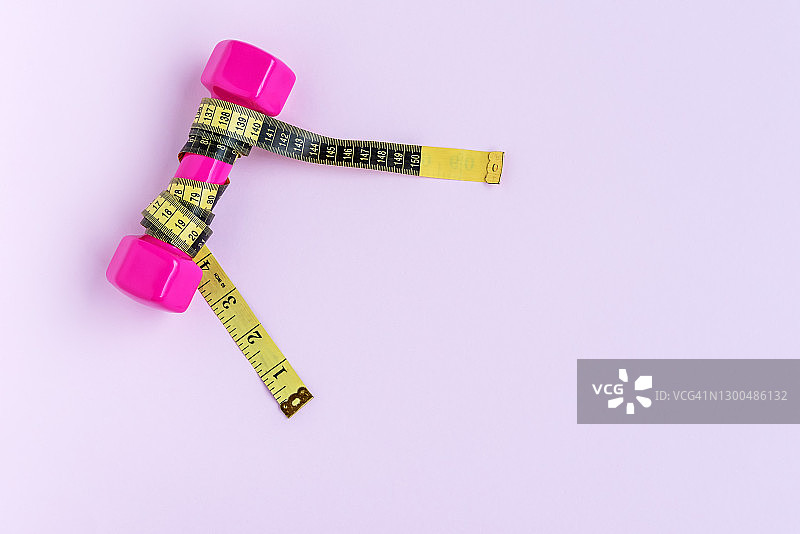 紫色背景上的哑铃和卷尺，带复制空间图片素材