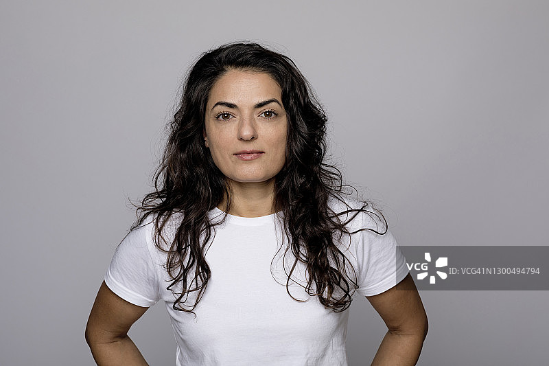 站在灰色背景前的黑色长发美女图片素材