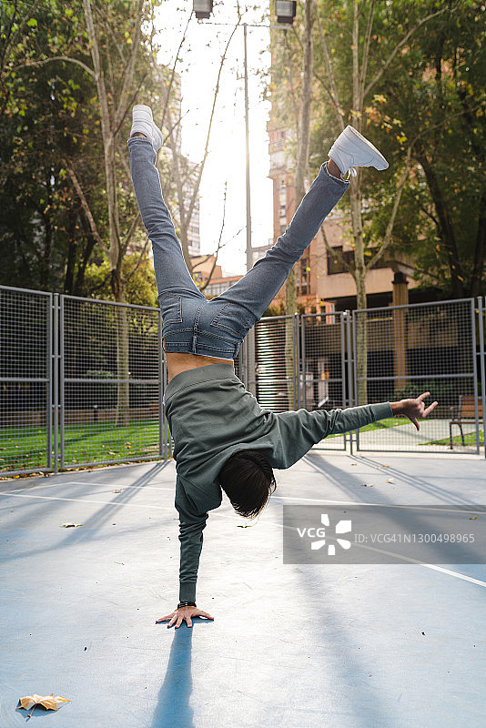 秋季校园篮球场上做倒立和摇滚手势的男人图片素材