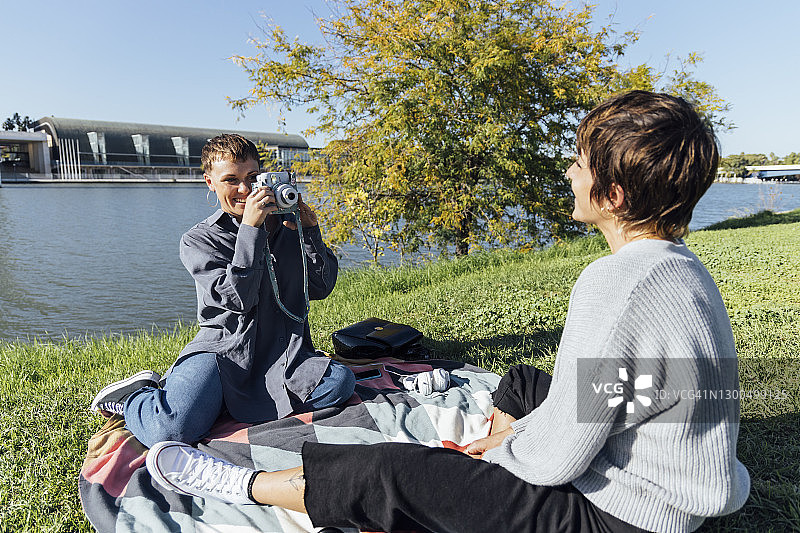 微笑的年轻女人在河边给朋友拍照图片素材