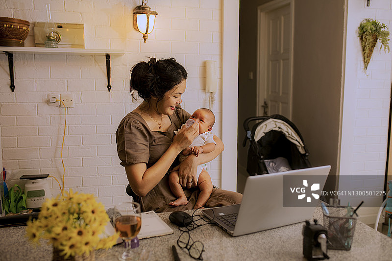 在家工作的亚洲母亲抱着可爱的宝宝图片素材