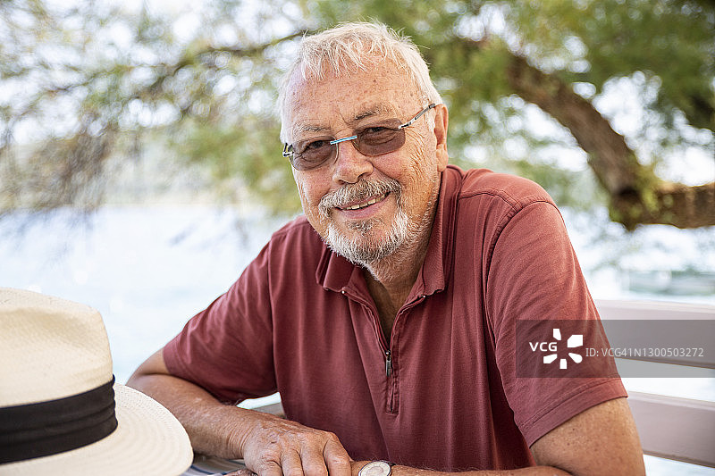 戴眼镜的年长男人在克罗地亚希贝尼克-克宁普里莫斯特的长椅上微笑图片素材