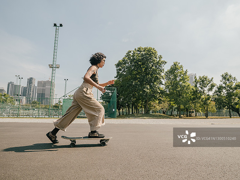 在阳光明媚的公园里玩滑板的少女图片素材