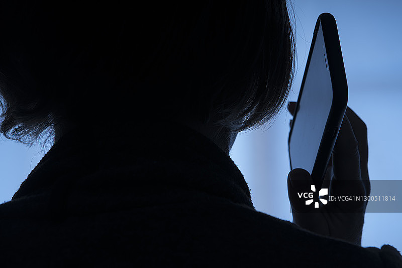 剪影：女人使用手机的背影特写图片素材