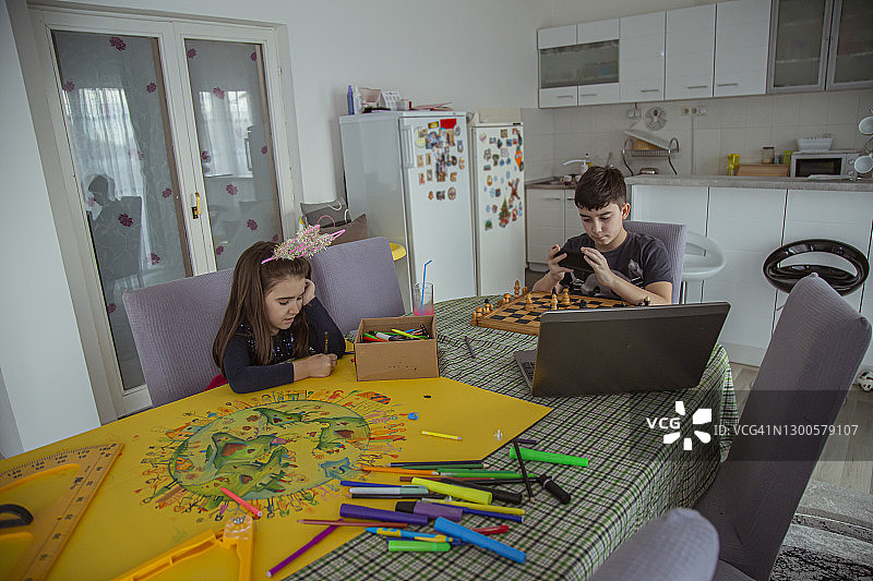 兄妹花时间在一起做他们的爱好：下棋和绘画图片素材