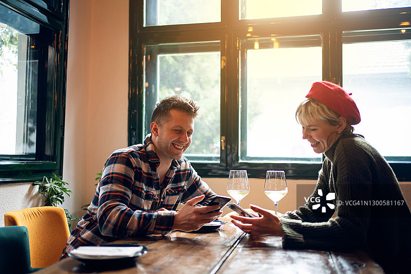 在餐厅用智能手机上网的快乐情侣图片素材