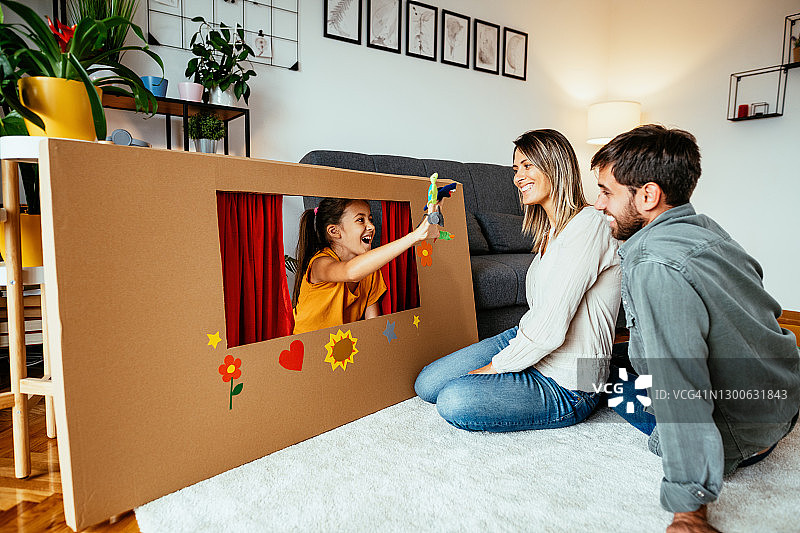 一家人和女儿在家玩耍，制作家庭影院，用手指木偶表演图片素材
