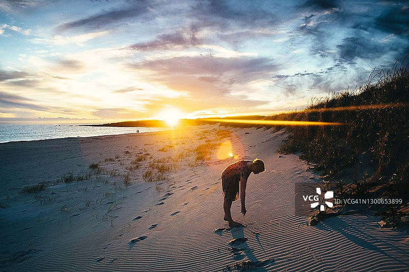 女人在夕阳下的海边行走图片素材