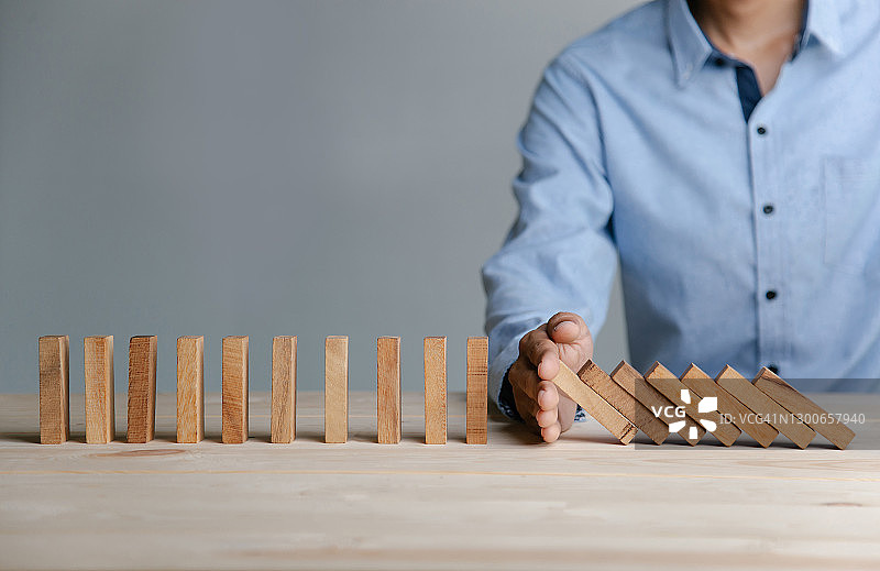 商人阻止多米诺骨牌效应，用于商业中的计划、风险和策略图片素材