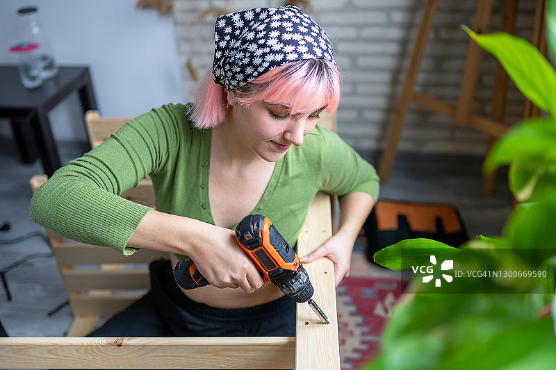 在家组装家具的粉色头发年轻女孩图片素材