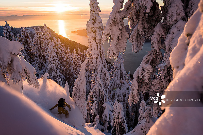日出时分，野外滑雪者在厚厚的粉雪中滑降图片素材