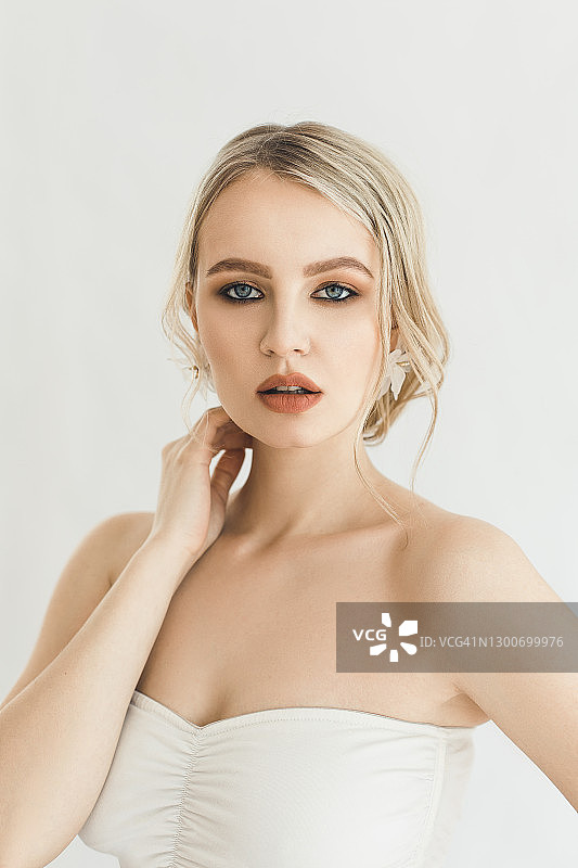 化着精致妆容、戴着漂亮大耳环的金发美女肖像，白色背景图片素材