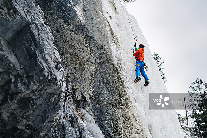 仰望攀冰者攀登高耸的冰冻瀑布图片素材