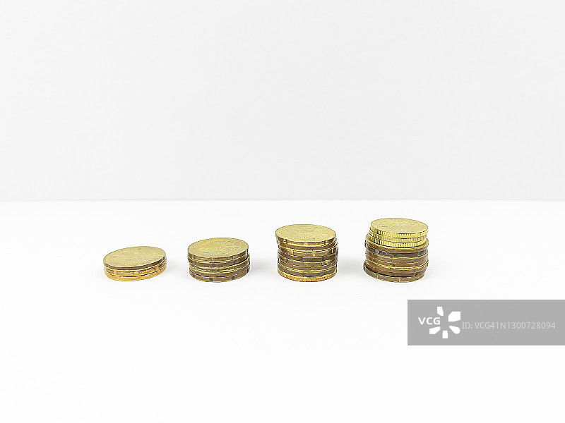 堆叠在木桌顶部的不同水平面上的金币。商业和金融概念。图片素材