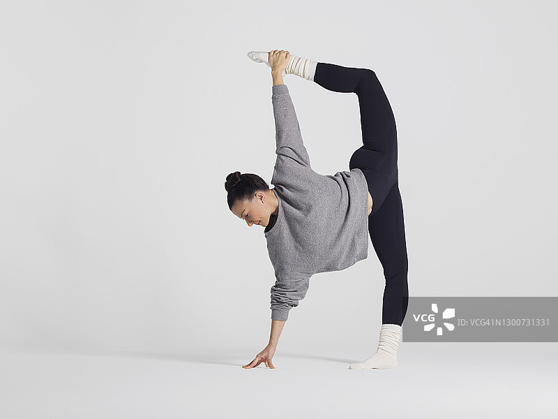 年长的运动型女人穿着运动服、裤子和上衣，练习瑜伽，工作室拍摄图片素材