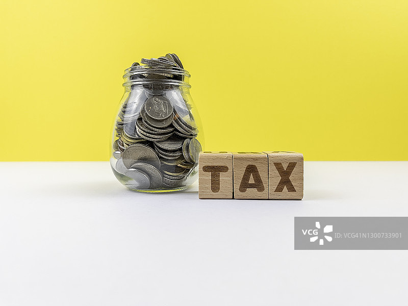 印有“税务”字样的积木和装满硬币的罐子图片素材