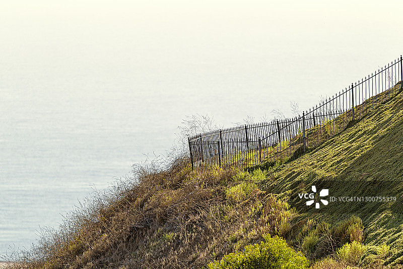 太平洋、锻铁栅栏和山丘景色图片素材