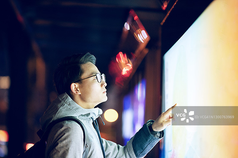 在公交车站使用触摸屏的年轻男人图片素材