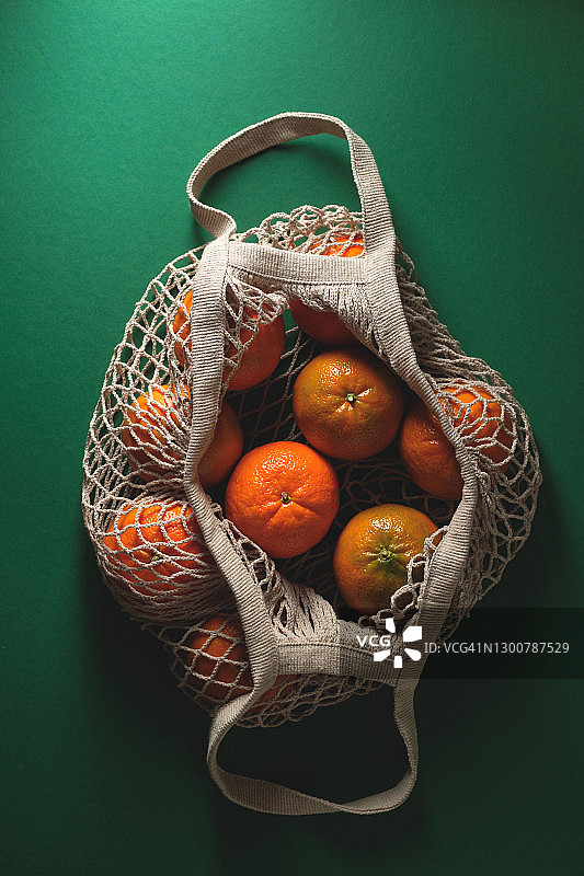 绿色背景下的再生材料环保袋中的未成熟橘子图片素材