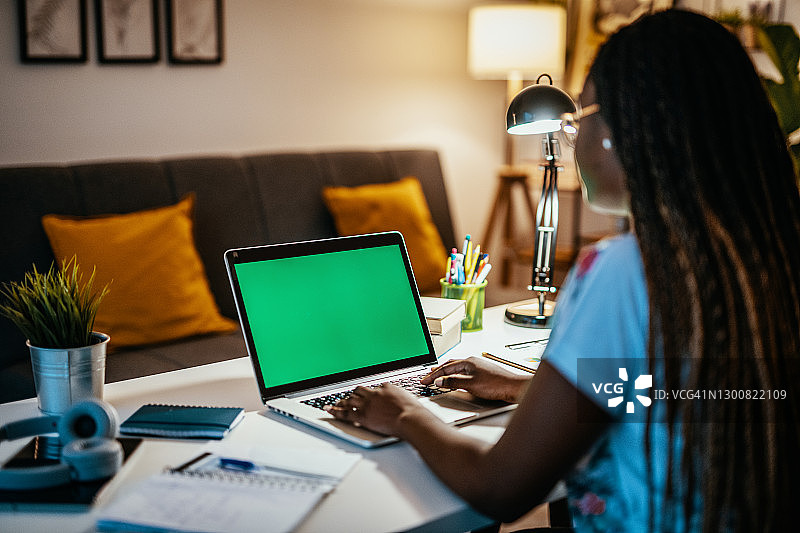 在笔记本电脑前使用色度键屏幕工作的非裔美国妇女（未识别面容）图片素材