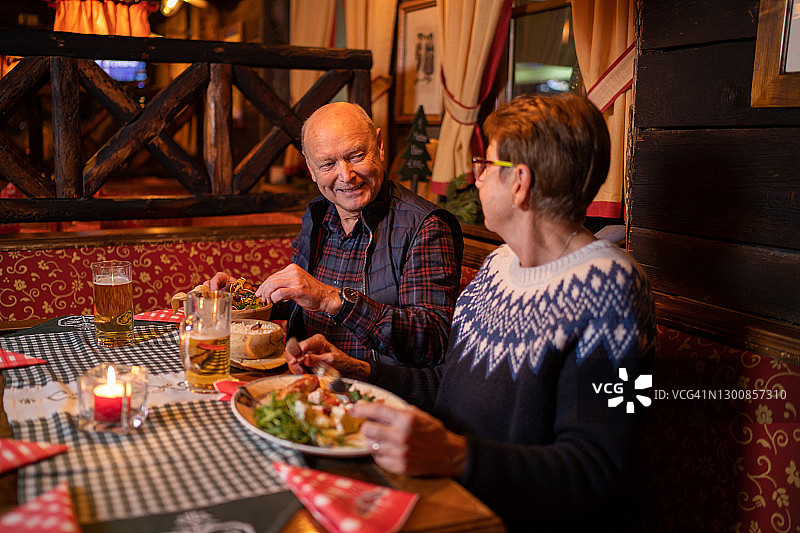 在冬季假期在餐厅享用晚餐的快乐老年夫妇图片素材