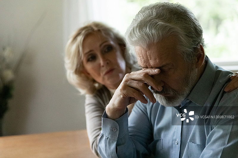 充满关怀的中年妇女安慰沮丧的丈夫，拥抱特写图片素材