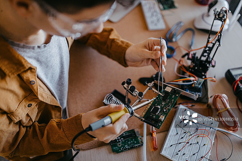 在电路板上焊接元件的少年图片素材