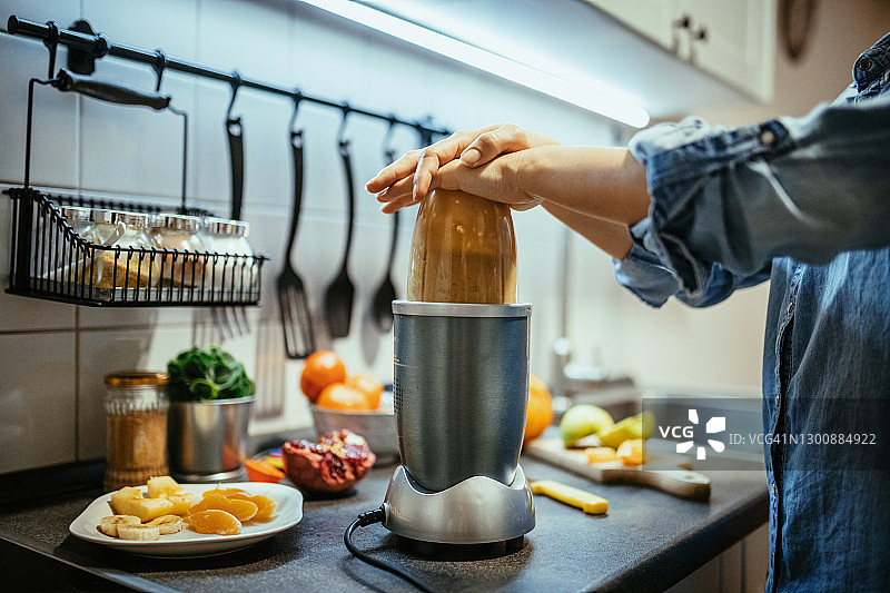 用电动搅拌机和水果制作冰沙的白人女性图片素材