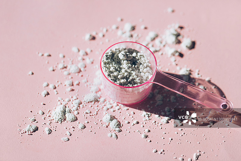 粉红色背景上的胶原蛋白粉或海藻酸盐面膜量勺图片素材
