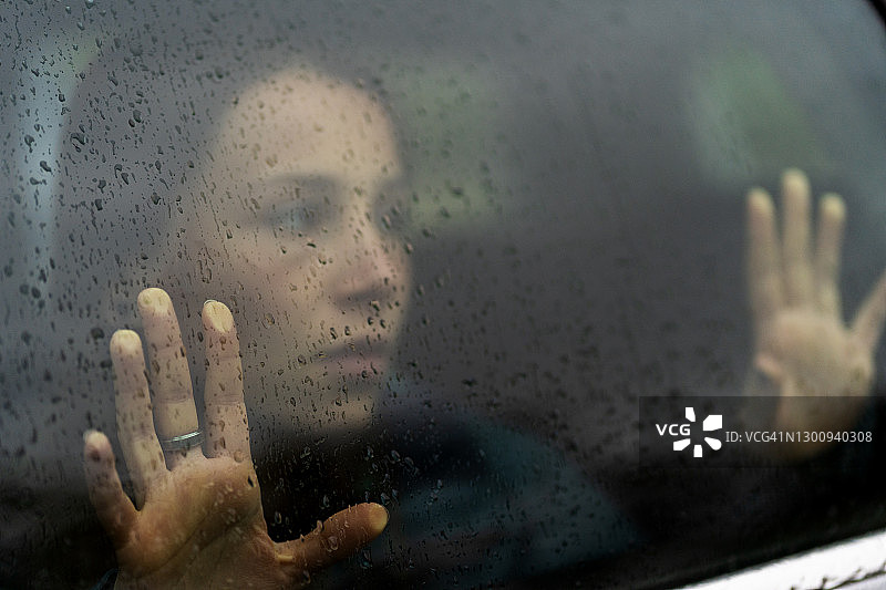 悲伤的女人在雨中看着窗外图片素材