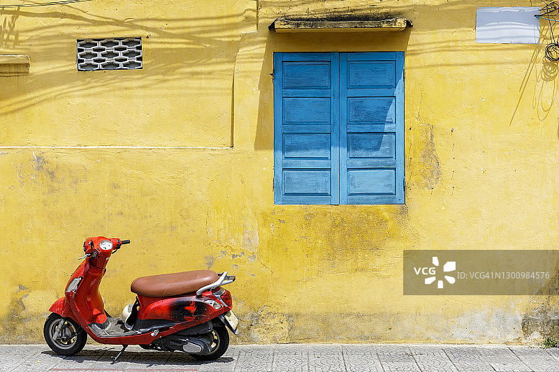 越南会安，黄色墙壁前的红色摩托车图片素材