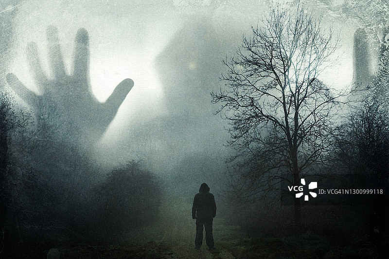 在阴沉的冬日乡村，男人抬头看着雾中出现的巨大幽灵兜帽身影，复古风格图片素材