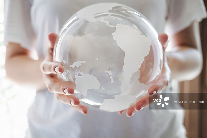 女人的手轻柔地捧着透明的地球仪，呵护生态环境图片素材