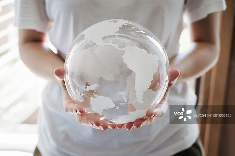 女人的手轻柔地捧着透明的地球仪，呵护生态环境图片素材
