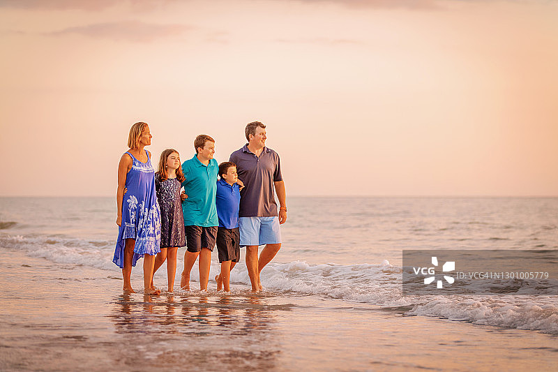 父母与三名儿童在浅海中行走图片素材