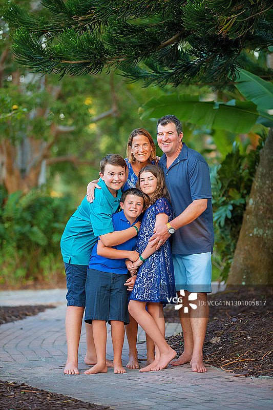 父母和三个孩子在人行道上拥抱合影，看着镜头图片素材