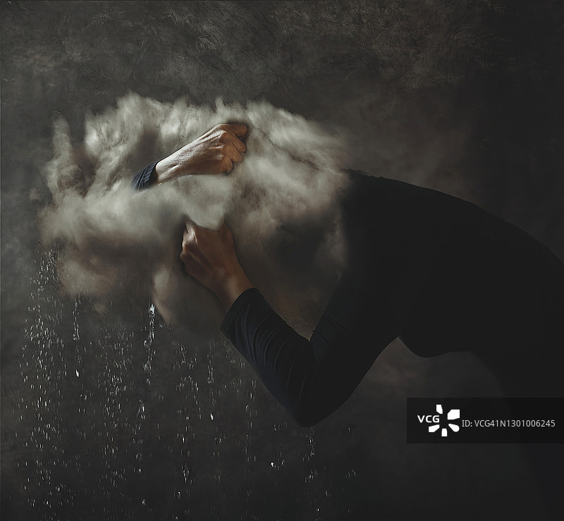 头顶乌云并挤压乌云使之开始下雨的人图片素材