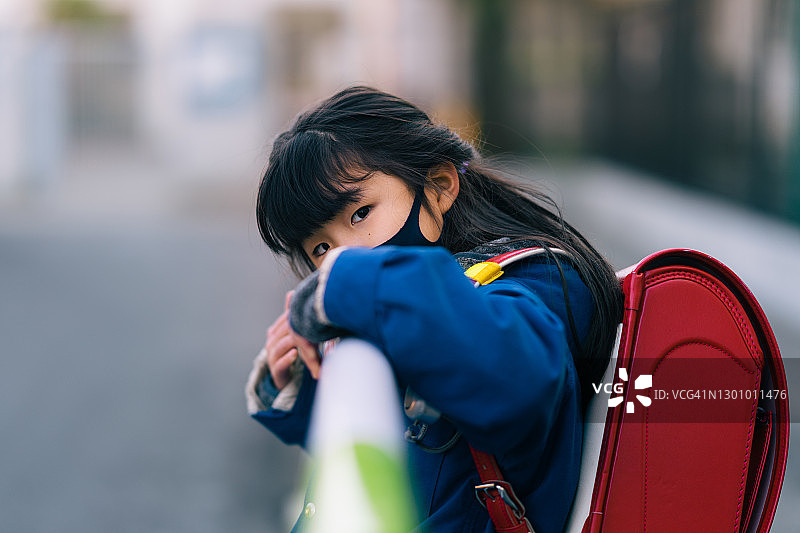 戴着防护口罩、面露担忧的小学年龄女孩看着镜头图片素材