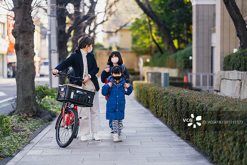 母亲和女儿们在街上行走，母亲上班，女儿们上学图片素材