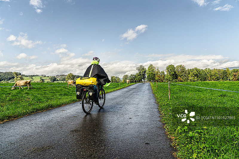在雨中自行车道上骑自行车的女自行车手图片素材