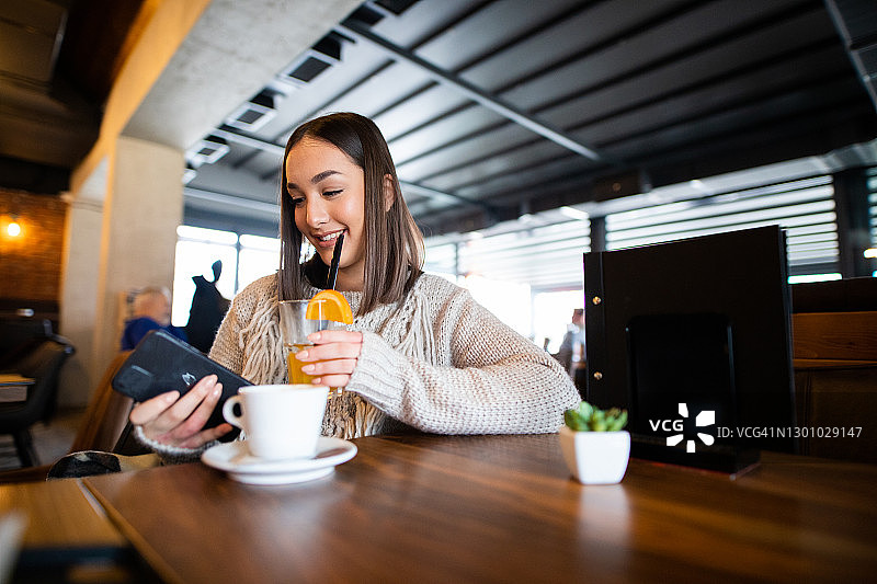 青少年女孩在咖啡馆看手机图片素材
