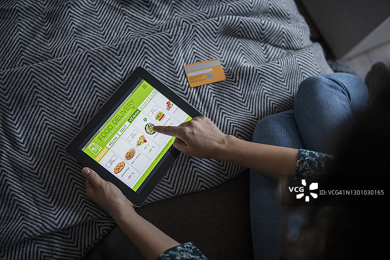 女人拿着一个显示食品配送菜单的平板电脑图片素材